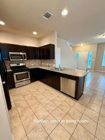 a open kitchen with kitchen island granite countertop a sink and a stove top oven