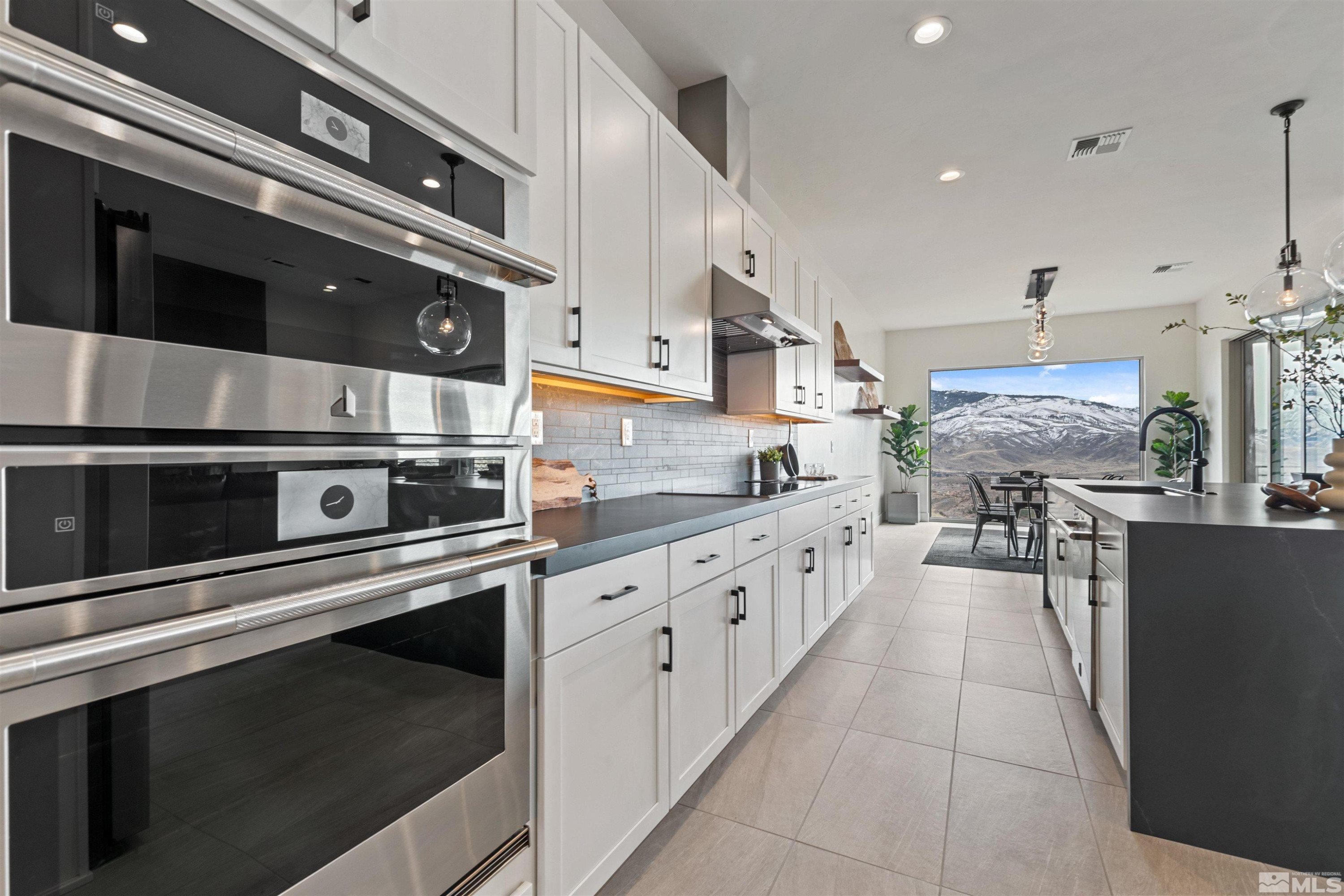 9110 Wild Skies Way Reno, NV 89523 - Photo 19 of 46 a kitchen with stainless steel appliances kitchen island granite countertop a stove a sink and a microwave