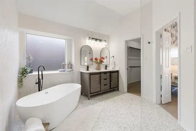 a spacious bathroom with a double vanity sink mirror and bathtub