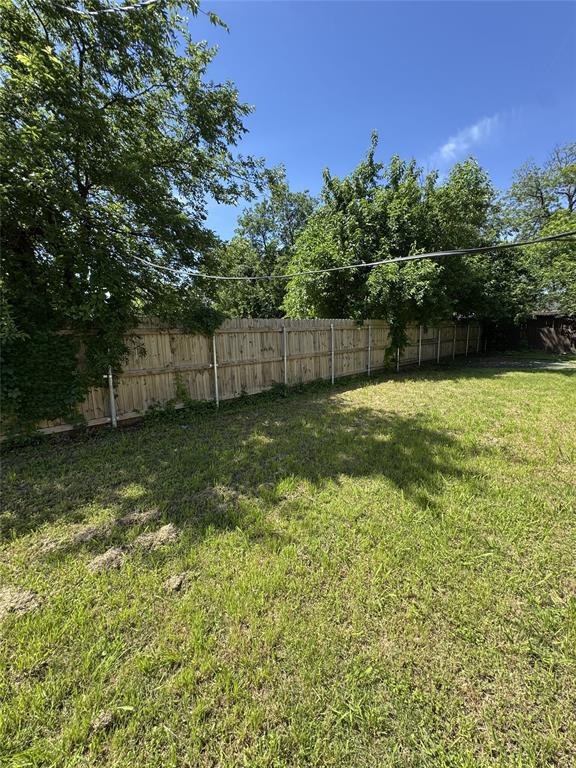 803 Ripley Avenue Ennis, TX 75119 - Photo 6 of 40 Fenced backyard featuring a large grassy area, mature trees, and a wooden privacy fence