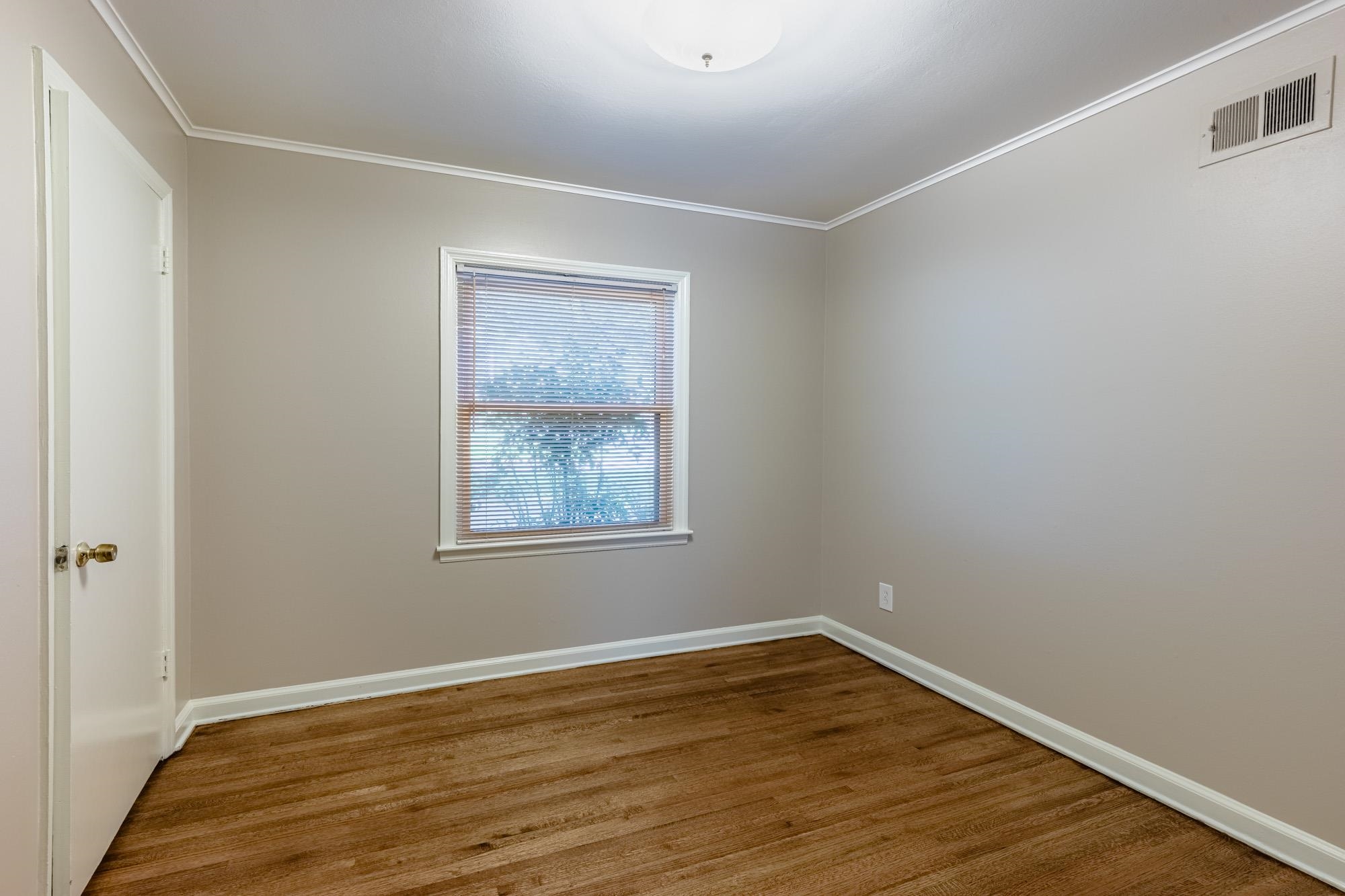 1081 Ivy Road Memphis, TN 38117 - Photo 8 of 25 a view of an empty room with wooden floor and a window