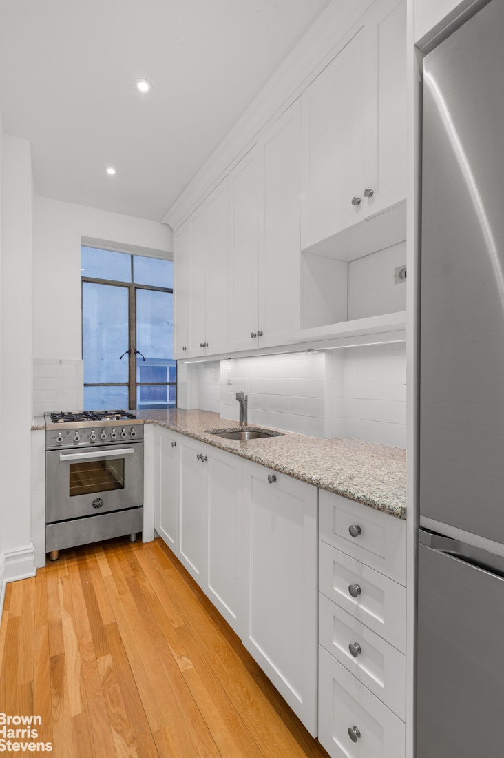 255 West 23rd Street, Unit 5B Manhattan, NY 10011 - Photo 5 of 9 a kitchen with granite countertop a stove oven and cabinets