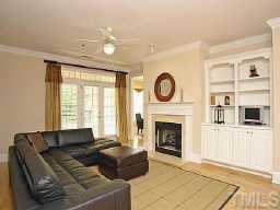 3701 Baron Cooper Pass, Unit 203 Raleigh, NC 27612 - Photo 3 of 10 Spacious living room with plenty of natural lighting! Features include warm gas lit fireplace with floor to ceiling built-in bookcases and cabinets, crown molding, 9ft ceilings, and beautiful laminate hardwood flooring!