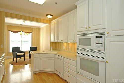 3701 Baron Cooper Pass, Unit 203 Raleigh, NC 27612 - Photo 5 of 10 Kitchen includes 42 cabinets with plenty of counter space, solid surface countertops, flat cook top, built-in microwave and oven, designer paint colors, several lighting options, and opens into breakfast nook