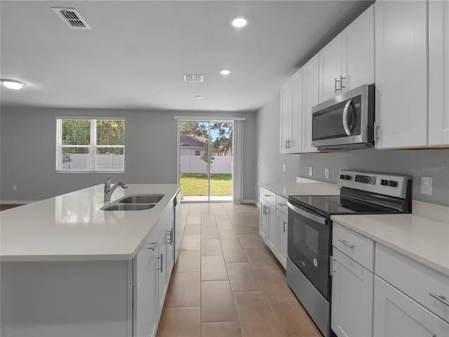 a kitchen with stainless steel appliances granite countertop a refrigerator sink and microwave