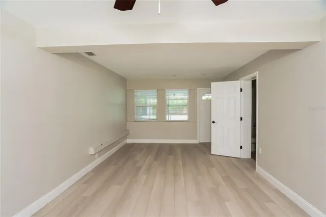 a view of an empty room with wooden floor and a window