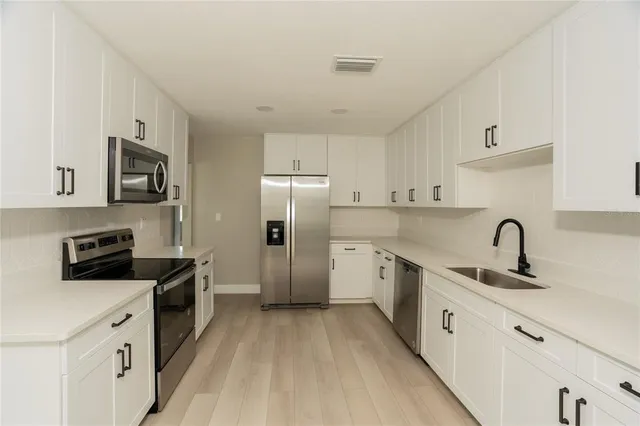 a kitchen with stainless steel appliances a sink stove refrigerator and cabinets