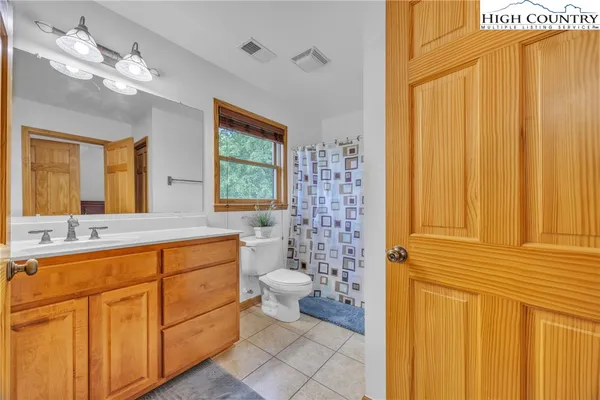 a bathroom with a granite countertop toilet a sink a mirror a window and a shower