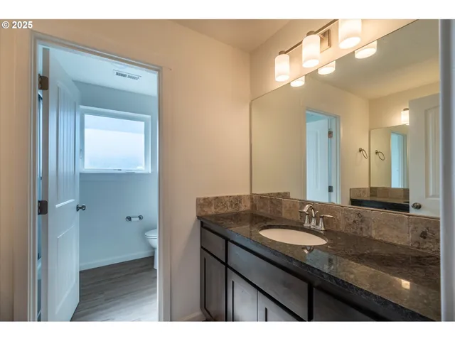 a bathroom with a granite countertop sink mirror and a toilet