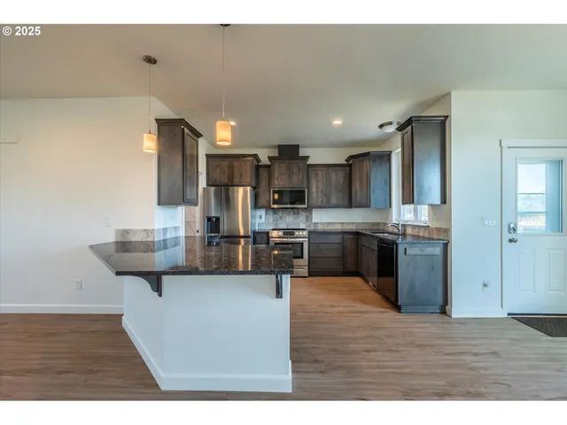 a kitchen with stainless steel appliances granite countertop a sink a stove and a refrigerator