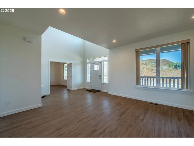 a view of an empty room with wooden floor and windows