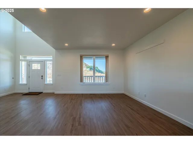 a view of an empty room with wooden floor and window