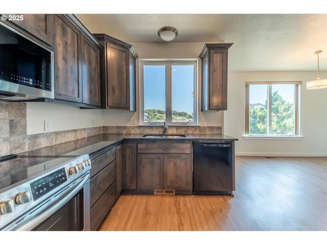 a kitchen with stainless steel appliances granite countertop a stove a sink and a microwave