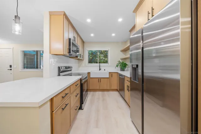 a large kitchen with stainless steel appliances kitchen island granite countertop a refrigerator a sink a stove and a refrigerator