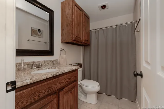 a bathroom with a granite countertop sink toilet and mirror