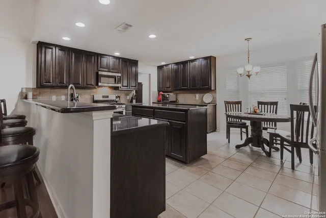 a kitchen with kitchen island granite countertop cabinets a sink a counter and appliances