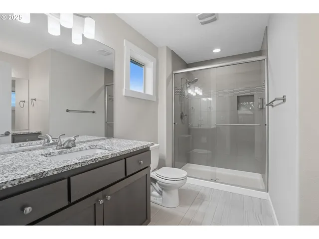 a bathroom with a granite countertop sink a toilet a mirror and shower