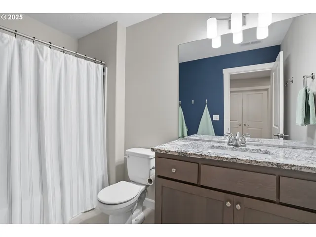 a bathroom with a granite countertop sink toilet and mirror