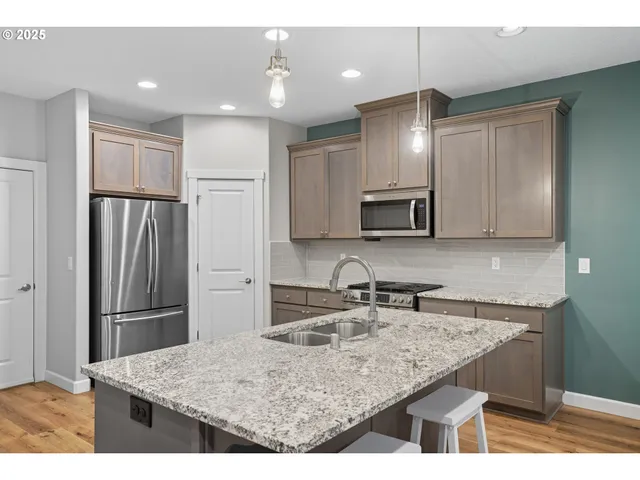 a kitchen with kitchen island granite countertop a refrigerator and a sink