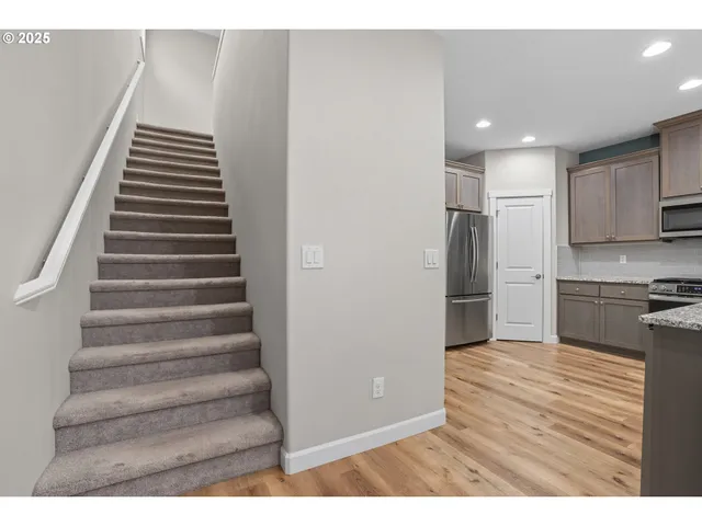 a view of kitchen and empty room with wooden floor
