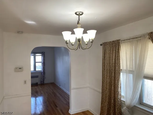 a view of a hallway with wooden floor and a chandelier