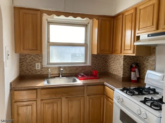 a kitchen with granite countertop a sink stove and cabinets