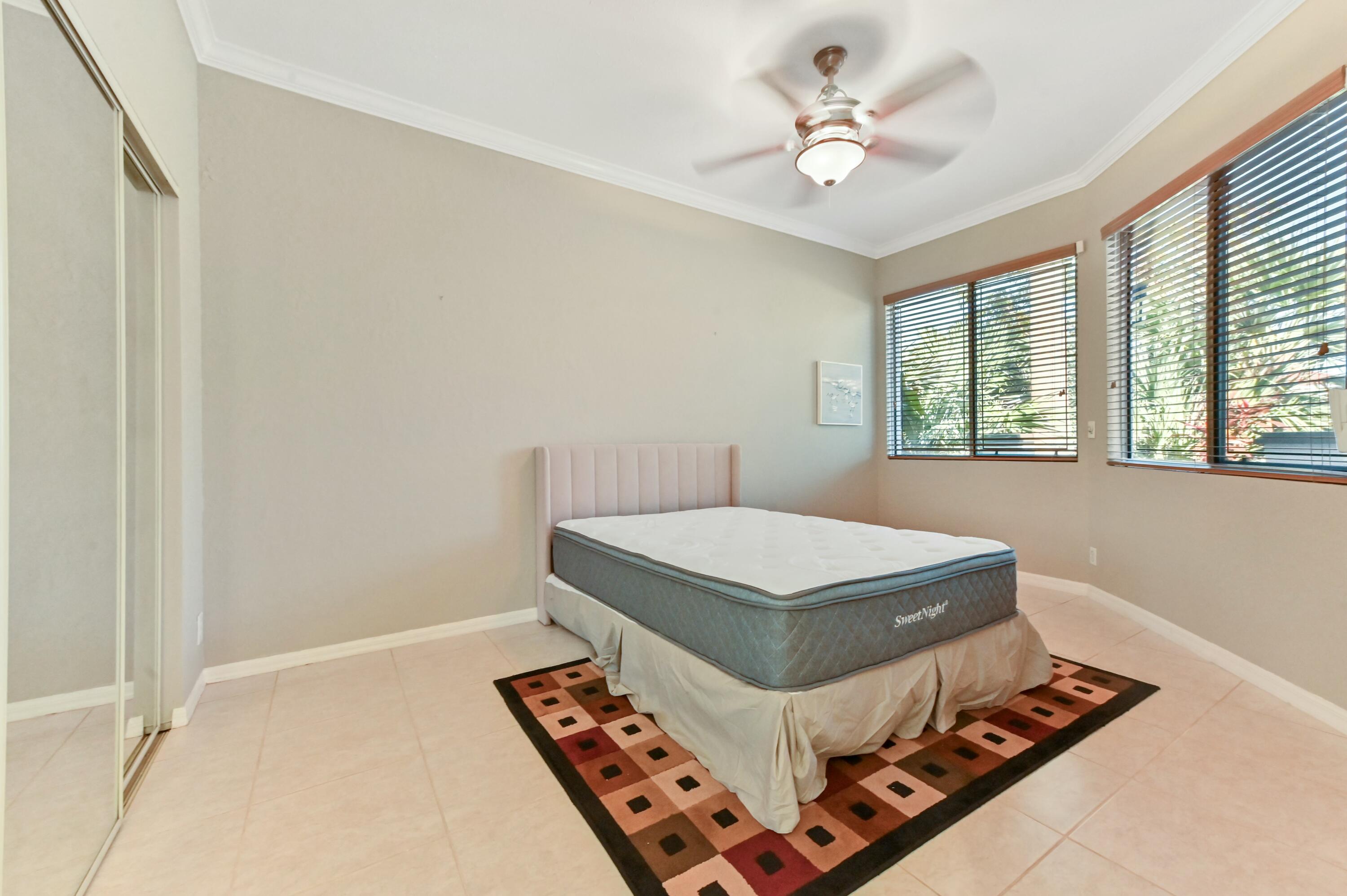 17272 Hampton Boulevard Boca Raton, FL 33496 - Photo 27 of 33 a bedroom with a bed and a chandelier fan