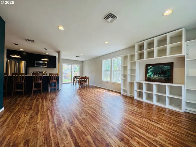 a view of an empty room with glass door and wooden floor