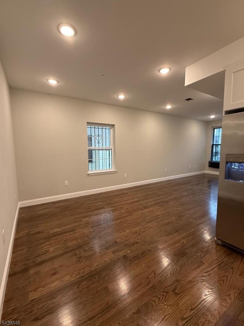 223 South 11th Street Newark, NJ 07107 - Photo 4 of 11 an empty room with wooden floor and windows