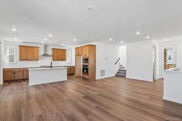 a large living room with stainless steel appliances kitchen view and wooden floor