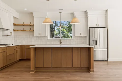 a kitchen with stainless steel appliances granite countertop a refrigerator a sink dishwasher a stove and a refrigerator