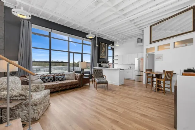 a living room with furniture a large window and wooden floor