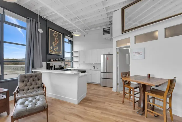 a kitchen with stainless steel appliances kitchen island granite countertop a refrigerator a stove and a wooden floors