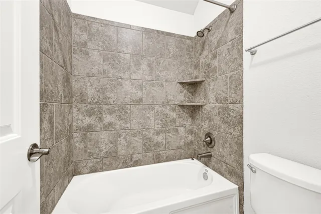 a bathroom with a white bath tub and a toilet