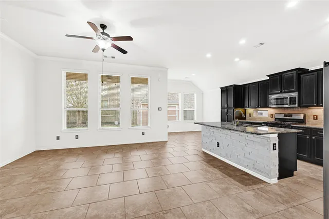 a large kitchen with stainless steel appliances granite countertop a stove top oven a sink a counter space and cabinets