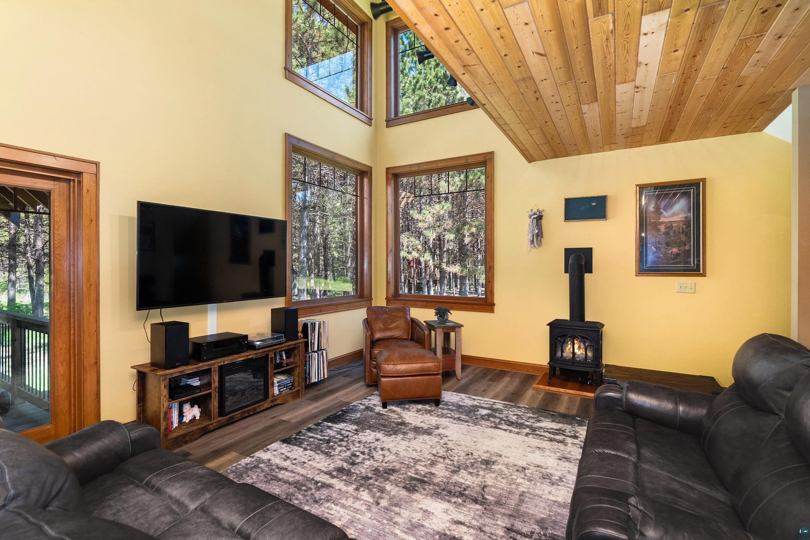 75 East Stark Road Esko, MN 55733 - Photo 12 of 87 Vaulted wood-paneled ceiling above a living area featuring wood-finish flooring, a wall-mounted television, and a black wood-burning stove