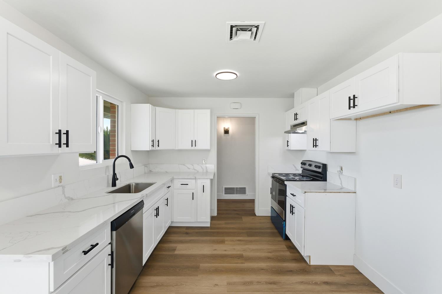 3473 East Dayton Avenue Fresno, CA 93726 - Photo 17 of 49 a kitchen with stainless steel appliances a sink stove top oven and cabinets