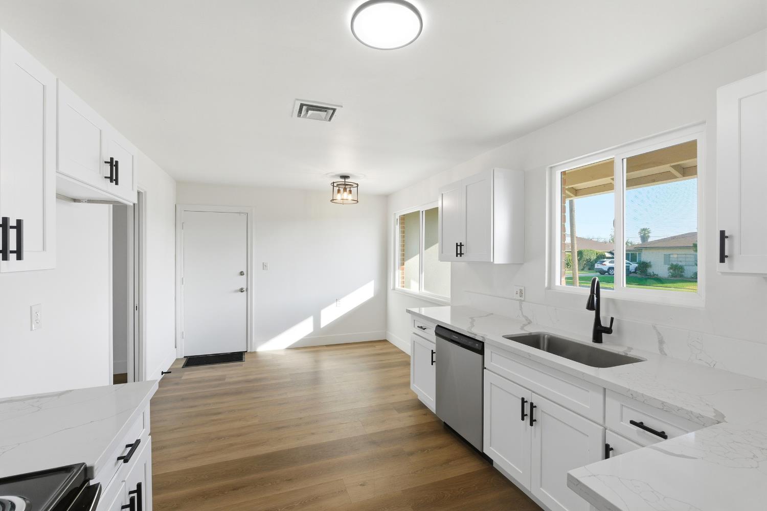 3473 East Dayton Avenue Fresno, CA 93726 - Photo 2 of 49 a large white kitchen with a sink and wooden floor