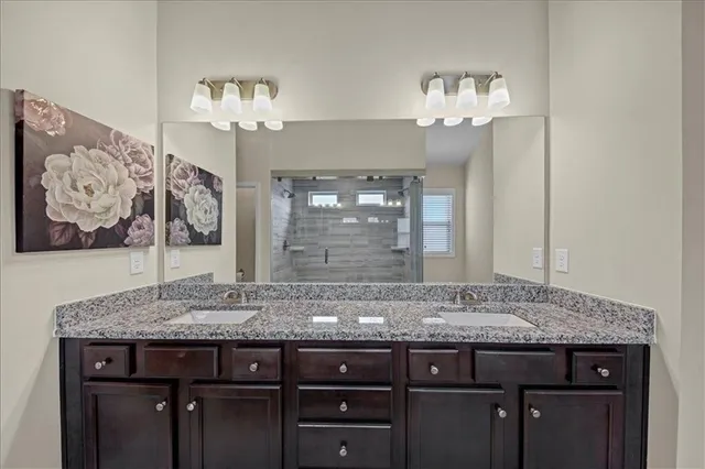 a bathroom with a granite countertop sink a mirror and a shower