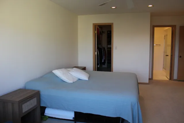 a bedroom with bed and flat tv screen next to a large window