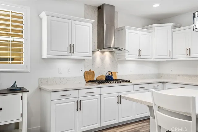 a kitchen with stainless steel appliances granite countertop a refrigerator a stove top oven a sink dishwasher and white cabinets with wooden floor