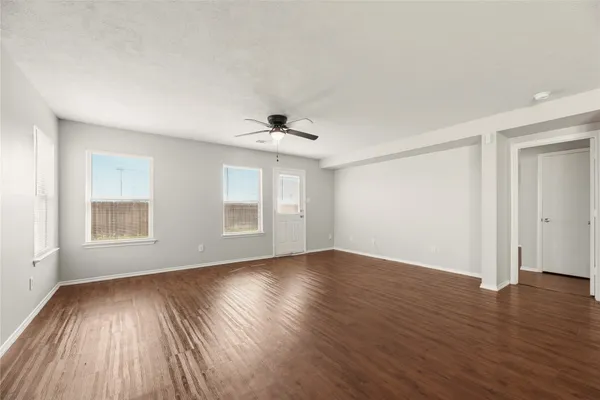 a view of an empty room with wooden floor and a window