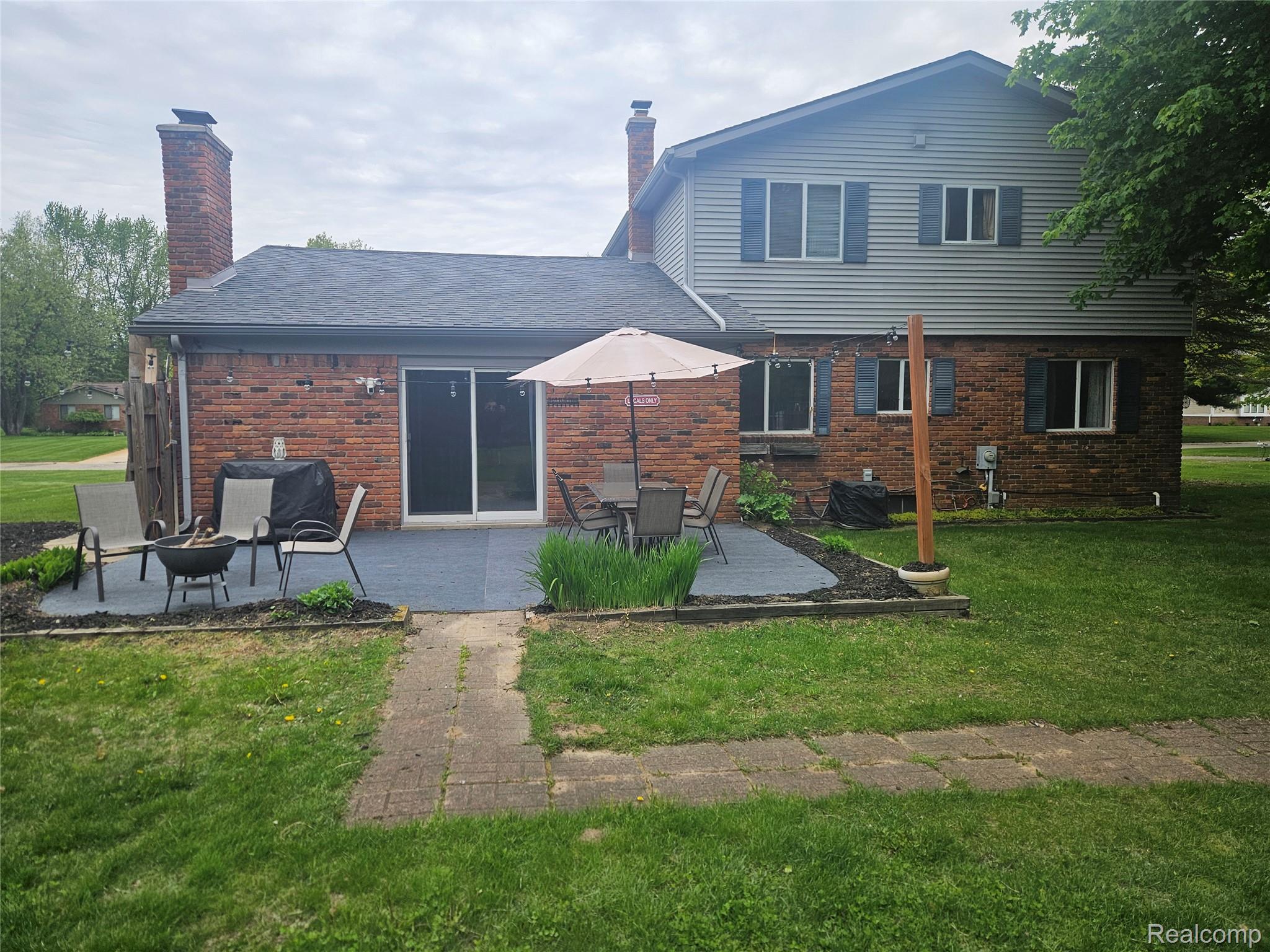 1210 Bay Ridge Drive Highland, MI 48356 - Photo 16 of 25 Rear view of house with a chimney, brick siding, a yard, and a patio area