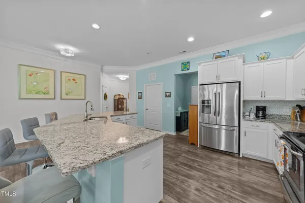 a kitchen with stainless steel appliances granite countertop a table chairs refrigerator and sink