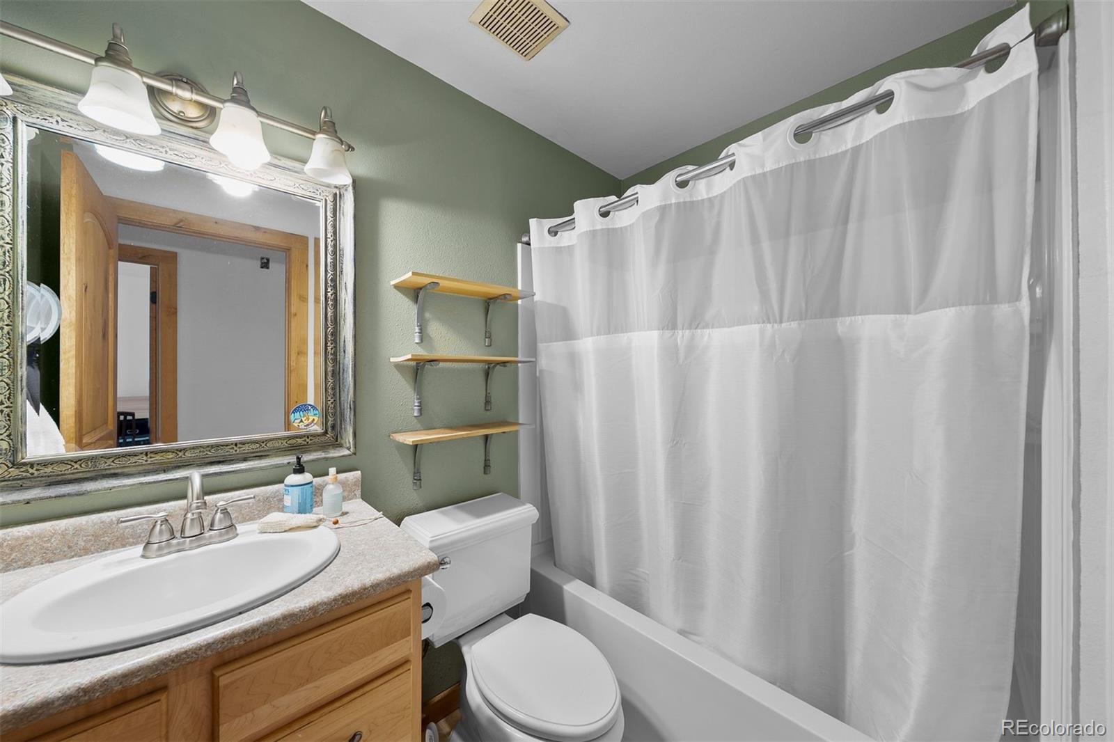 4466 West Parkridge Road Sedalia, CO 80135 - Photo 15 of 23 a bathroom with a sink a toilet a mirror and shower curtain