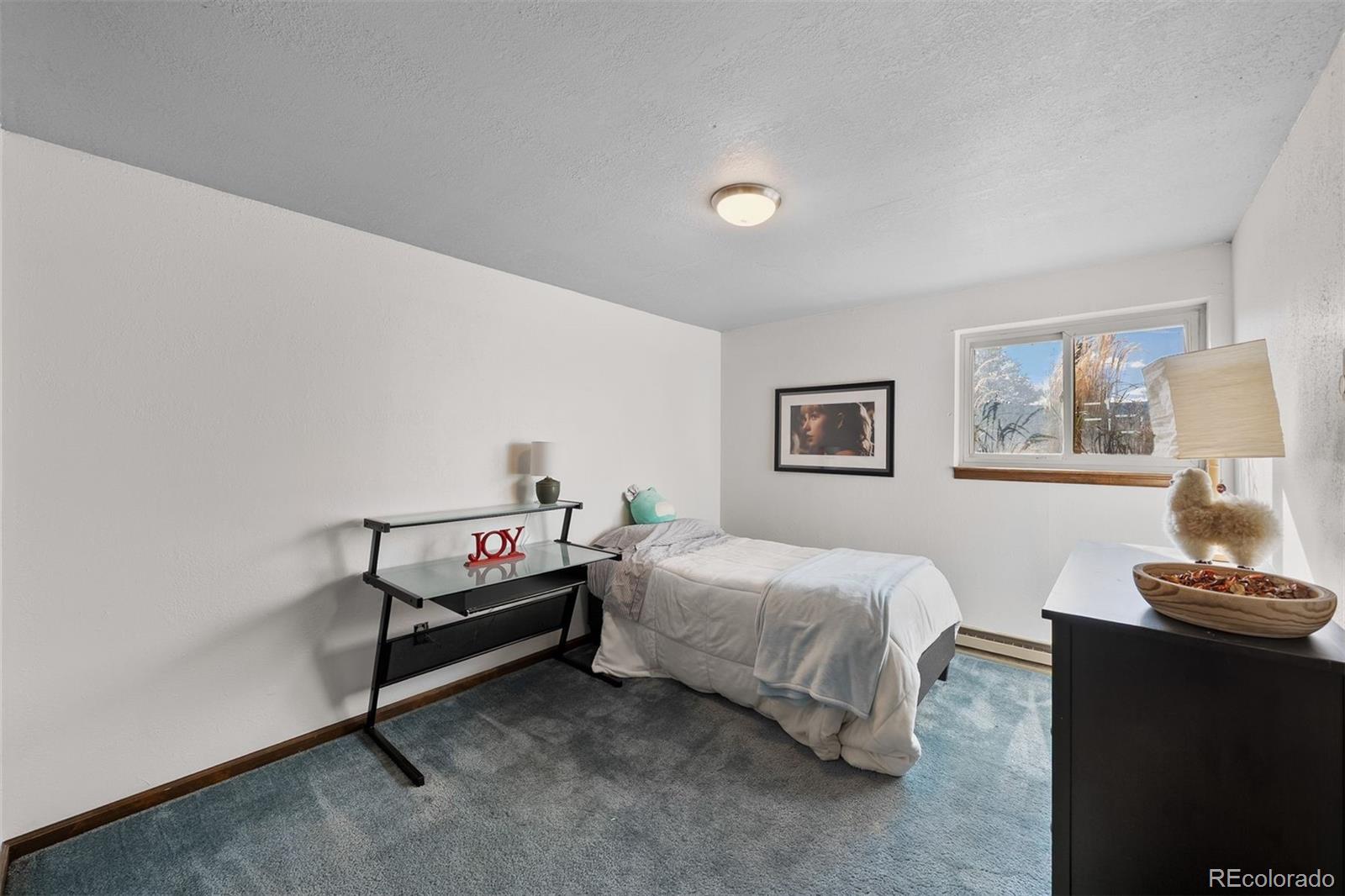 4466 West Parkridge Road Sedalia, CO 80135 - Photo 17 of 23 a bedroom with a bed and a lamp on a dresser