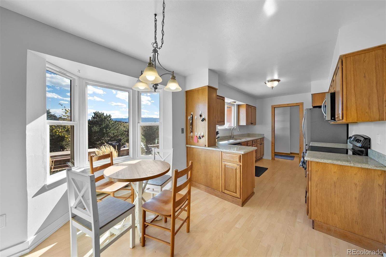 4466 West Parkridge Road Sedalia, CO 80135 - Photo 4 of 23 a kitchen with sink refrigerator dining table and chairs