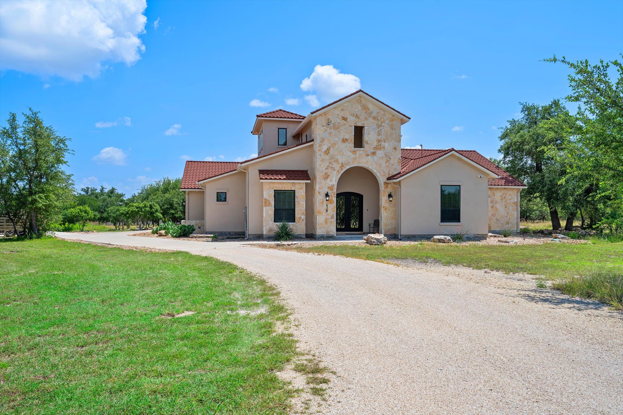 638 Strada Luca Florence, TX 76527 - Photo 5 of 38 An inviting gravel driveway leads to this elegantly constructed home featuring striking arched entryways and a tiled roof.