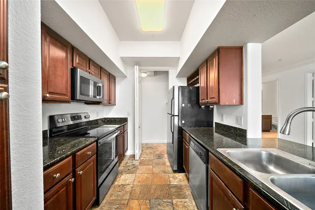 a kitchen with stainless steel appliances granite countertop a sink stove microwave and refrigerator