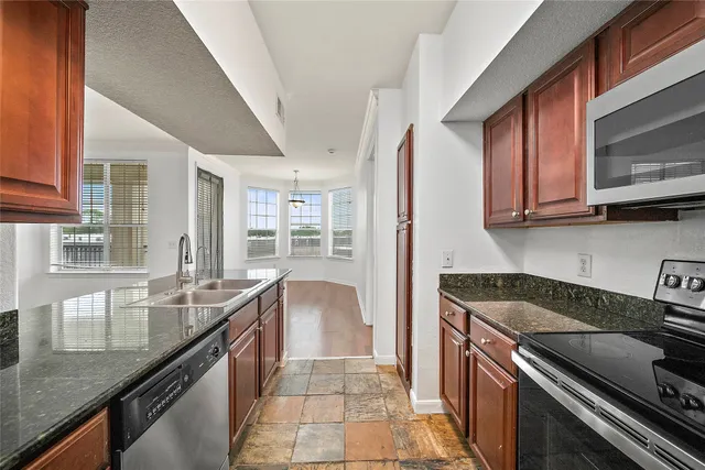 a kitchen with granite countertop a sink stove and cabinets
